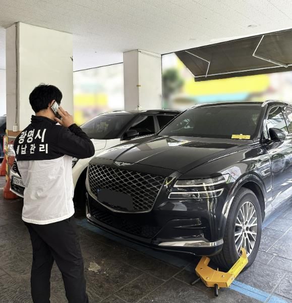 체납관리원이 체납차량에 대해 차량 이동제한장치를 설치하고 있는 모습.